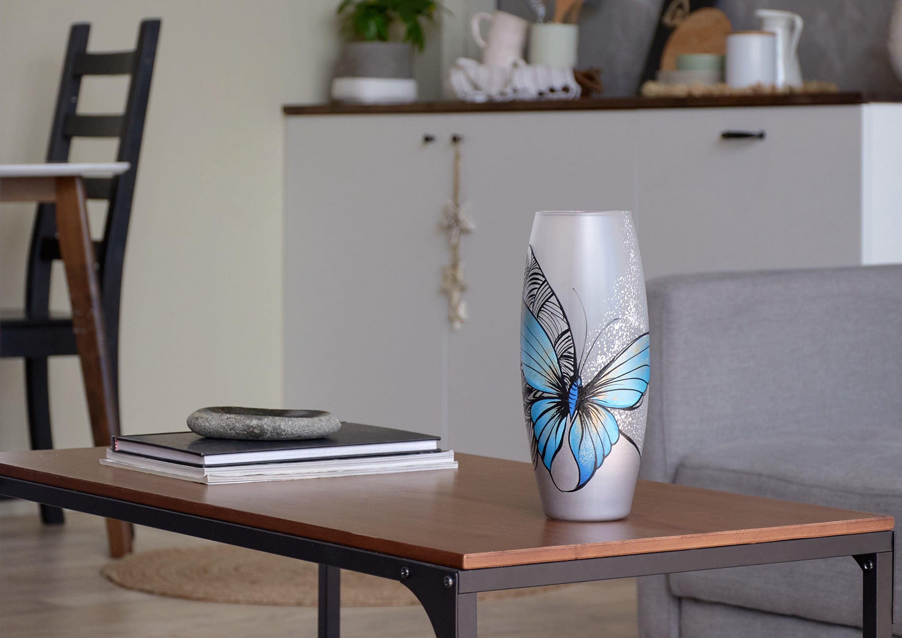 A beautifully hand-painted glass vase featuring a blue butterfly design, showcasing intricate artistry and vibrant colors, perfect for floral arrangements.