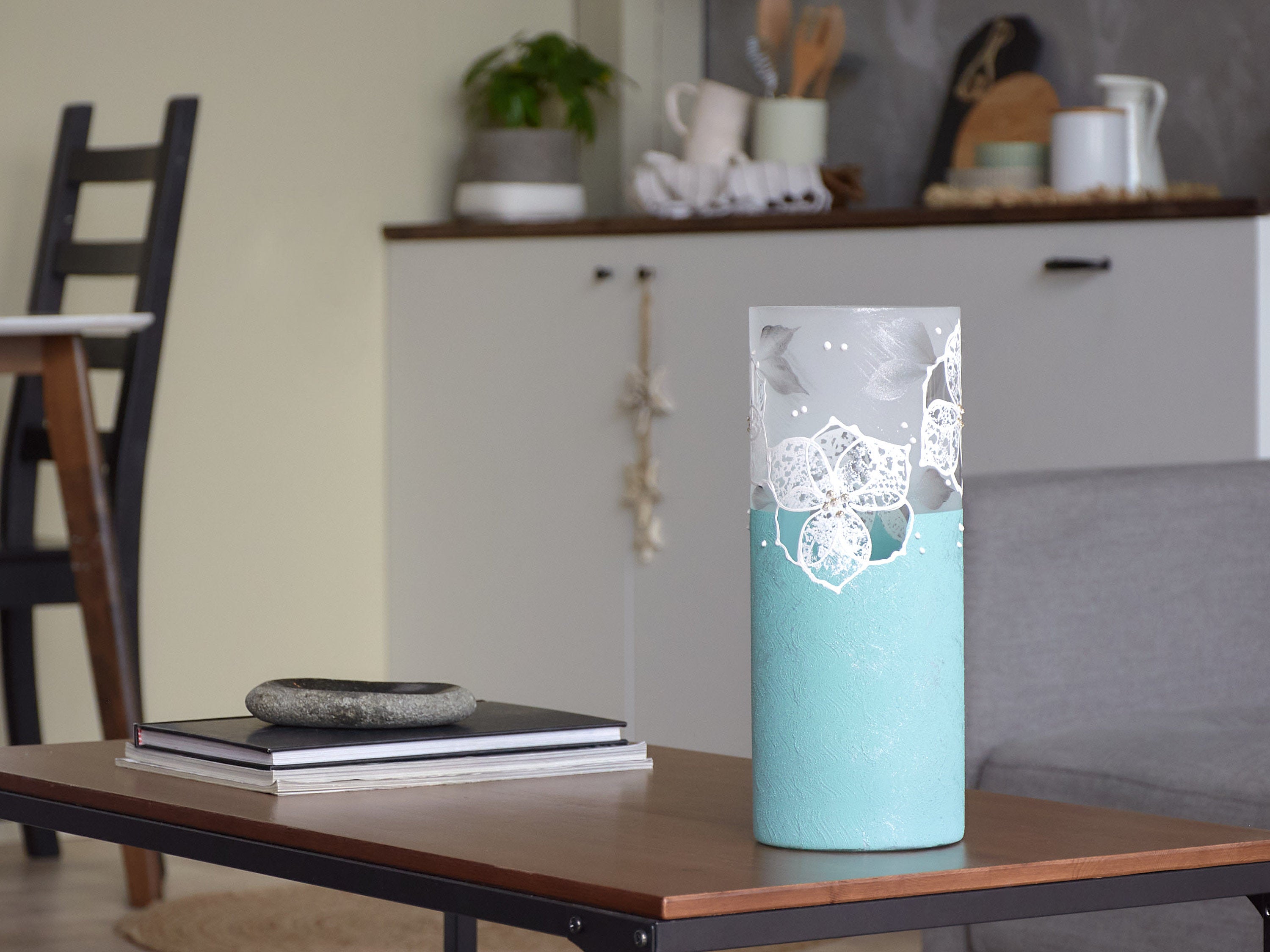 A beautifully hand-painted blue glass vase featuring unique floral and geometric designs, perfect for displaying flowers.
