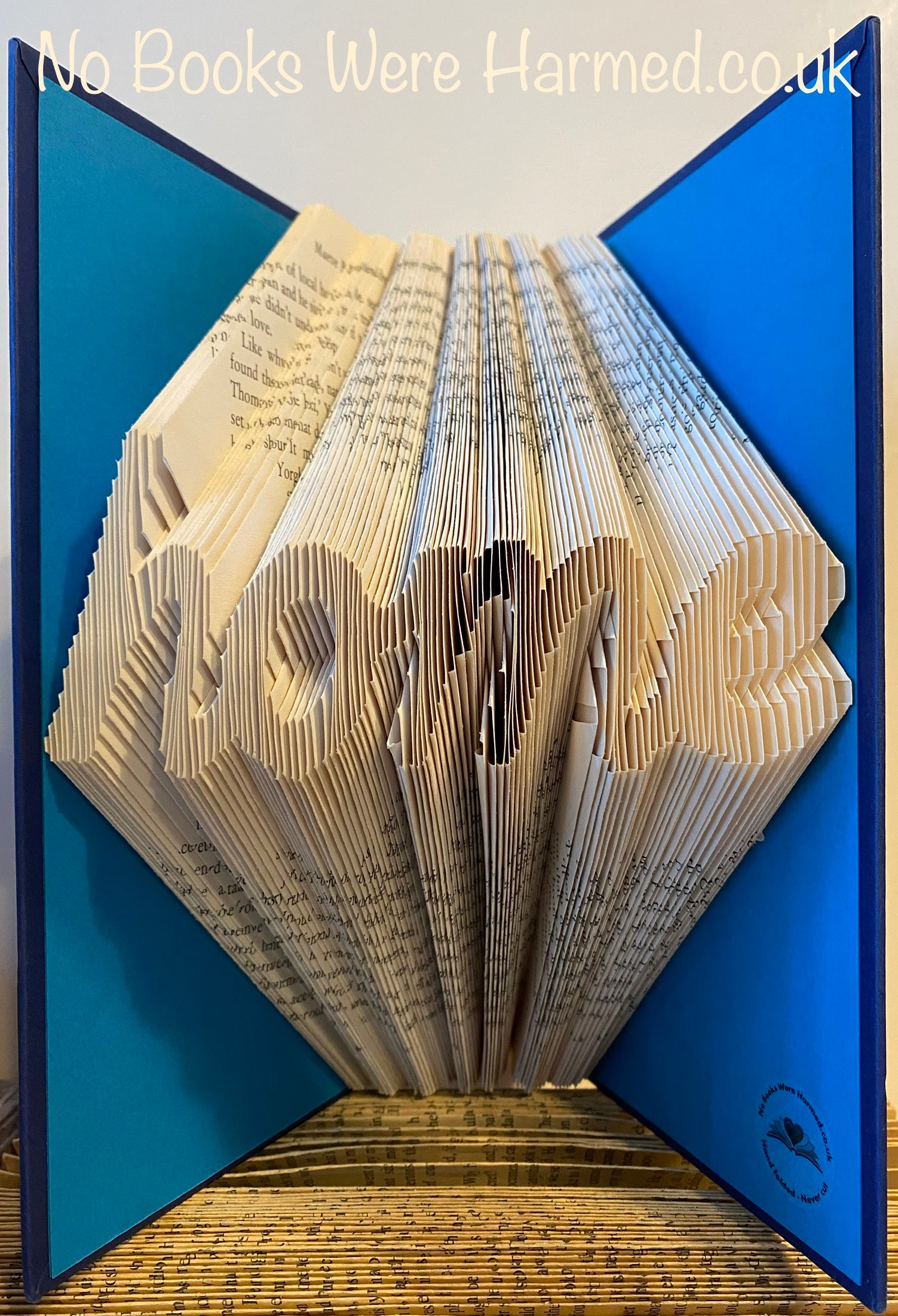 Handcrafted 'home' cursive art made from vintage book pages, showcasing unique folds and colors.