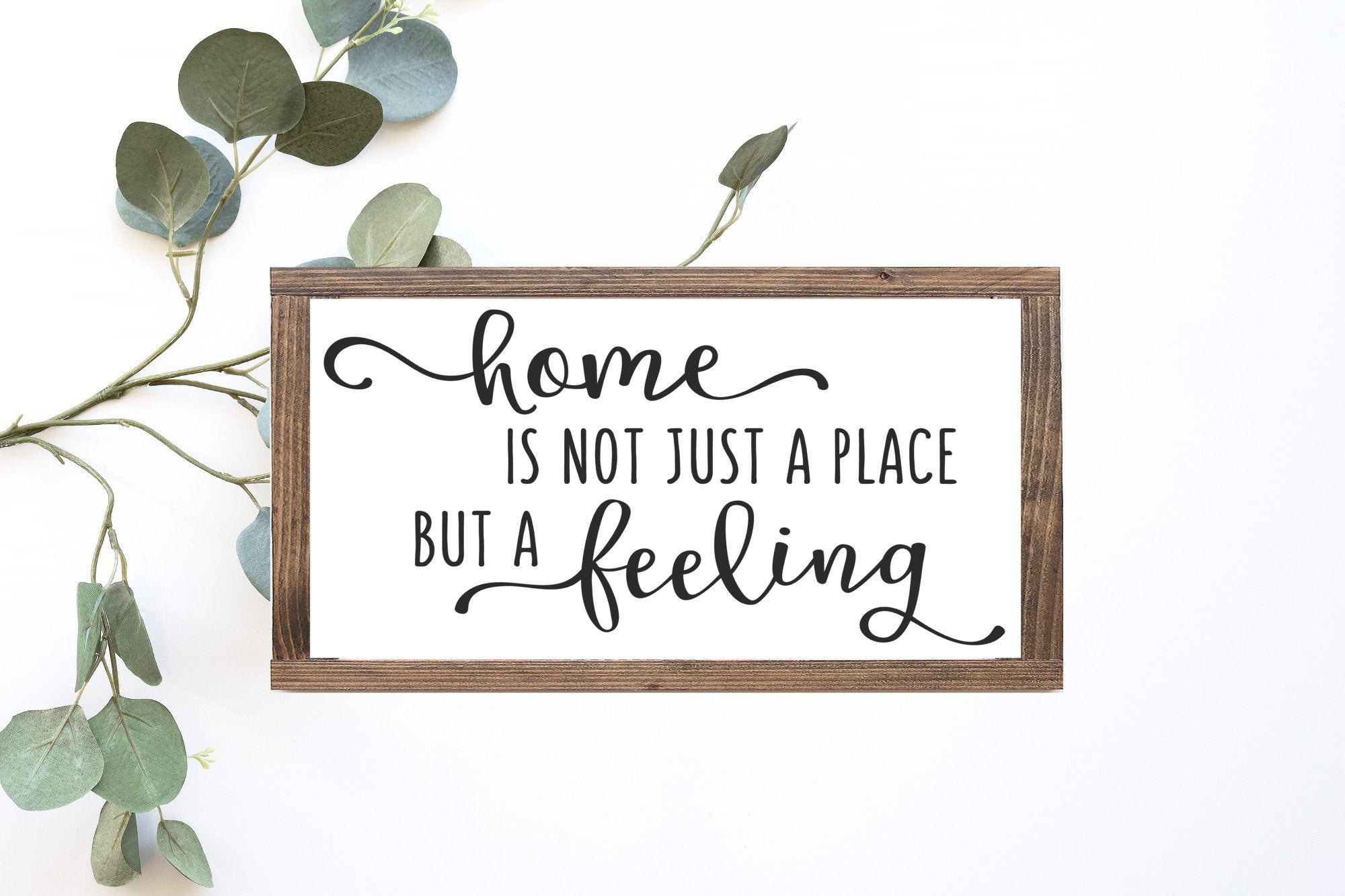 Handcrafted wood sign reading 'Home Is Not Just A Place But A Feeling', featuring a matte white background and unique wood grain.