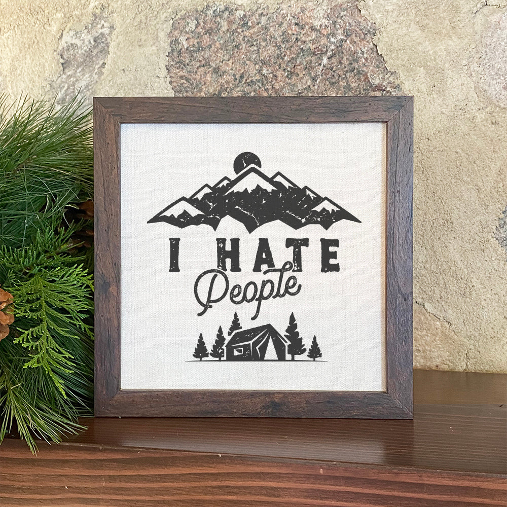 Framed sign with the text 'I Hate People' in a stylish wood frame, featuring a linen-look background.