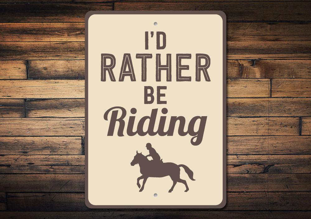 A decorative 'I'd Rather Be Riding' sign made of high-quality aluminum, featuring a rustic design suitable for indoor and outdoor display.