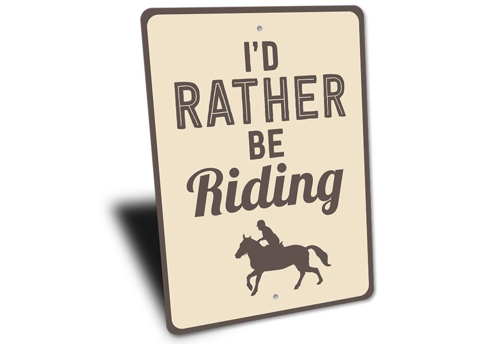 A decorative 'I'd Rather Be Riding' sign made of high-quality aluminum, featuring a rustic design suitable for indoor and outdoor display.