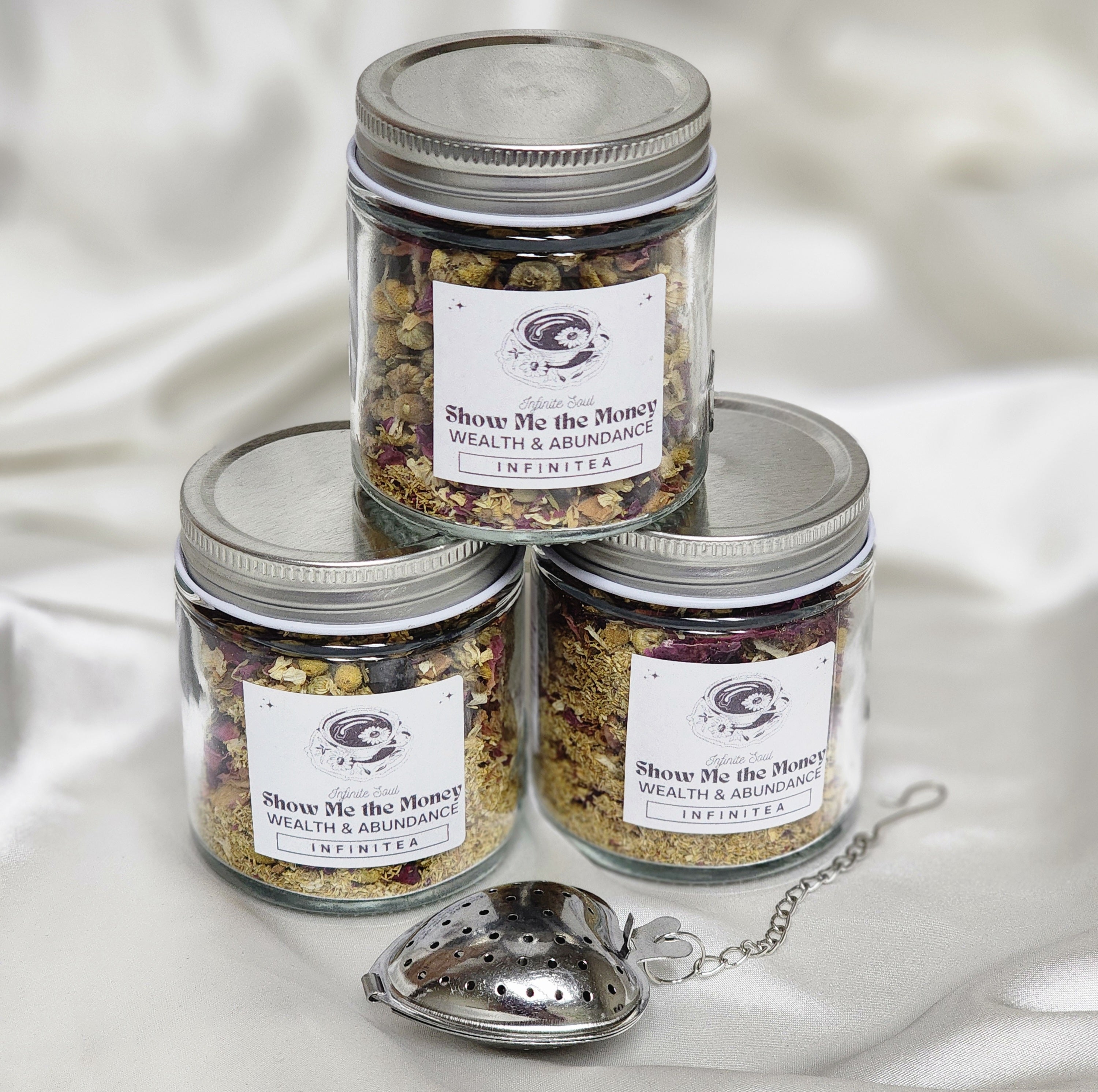 A vibrant package of Infinitea Show Me The Money herbal tea featuring colorful herbs and flowers, symbolizing wealth and abundance.