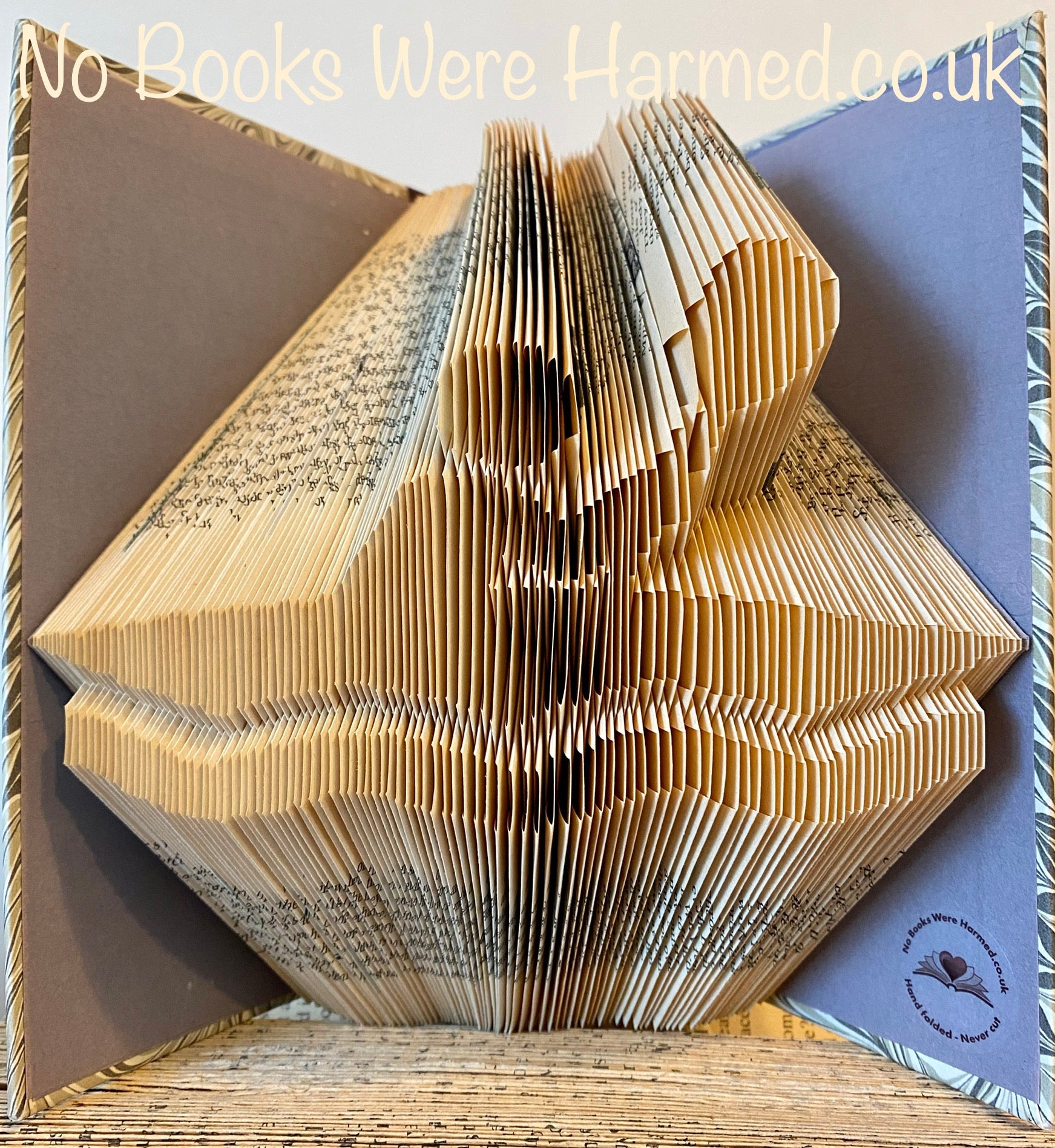 Unique hand-folded book art depicting kayaks and canoes, crafted from vintage books, showcasing intricate designs and eco-friendly artistry.