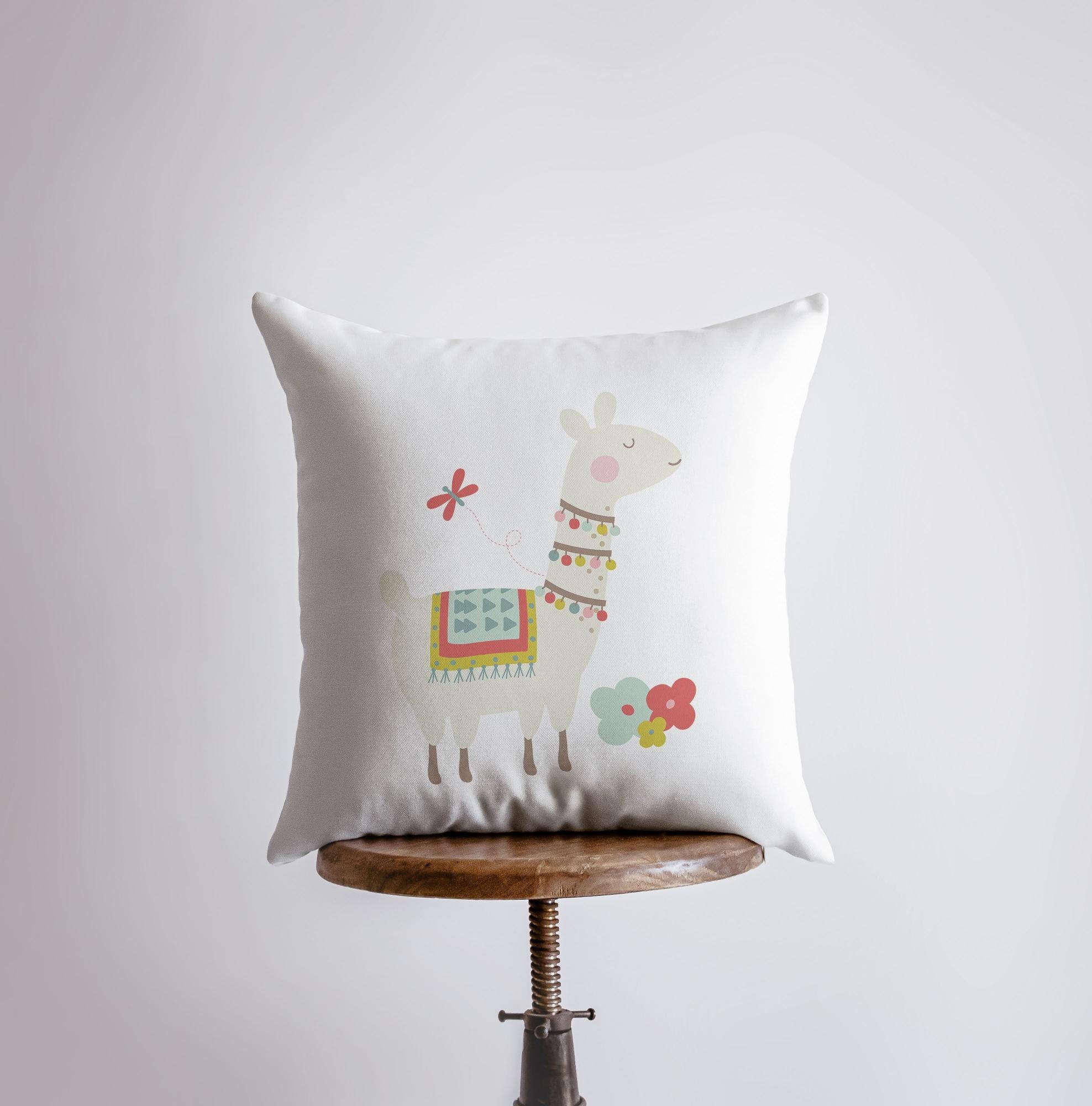 A charming Llama with Necklace pillow featuring a cute llama design on the front and a white back, perfect for Southwest decor.