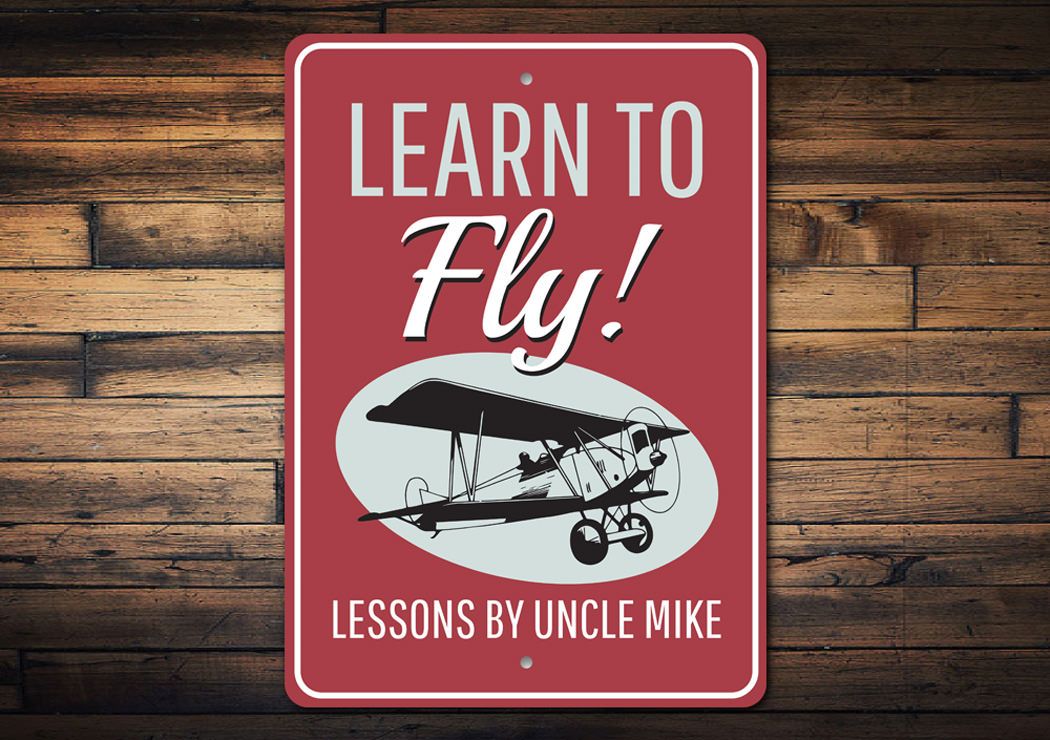 Learn to Fly Plane Lessons Sign made of high-quality aluminum, featuring customizable text and pre-drilled holes for easy mounting.