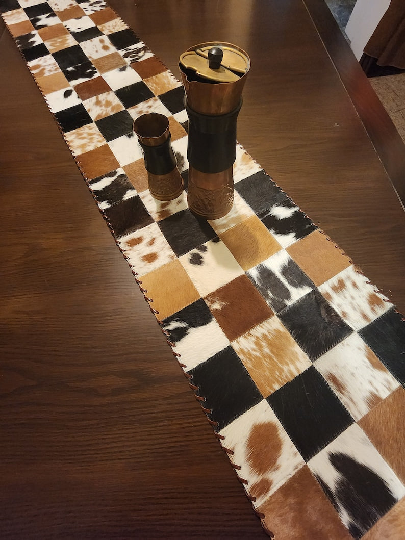 A stylish 16" x 96" leather cow skin table runner featuring a unique star pattern, perfect for enhancing home decor.