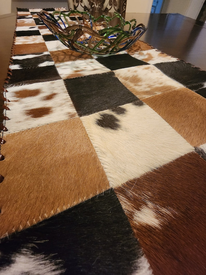 A stylish 16" x 96" leather cow skin table runner featuring a unique star pattern, perfect for enhancing home decor.