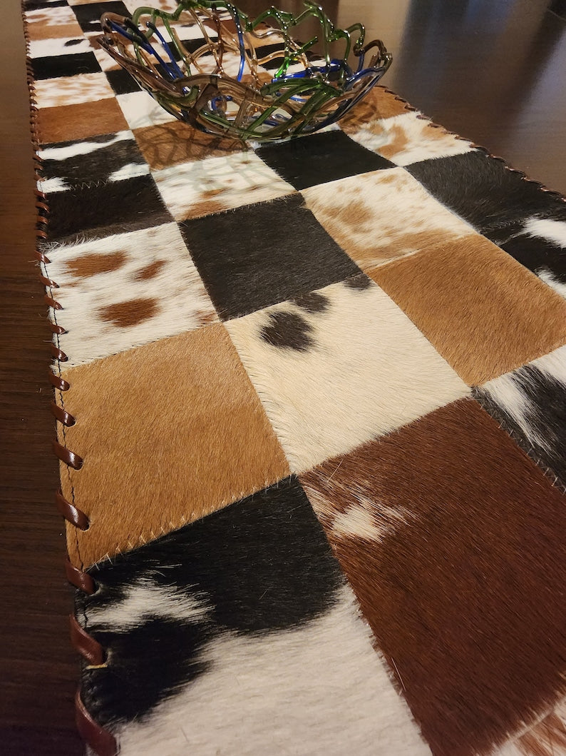 A stylish 16" x 96" leather cow skin table runner featuring a unique star pattern, perfect for enhancing home decor.