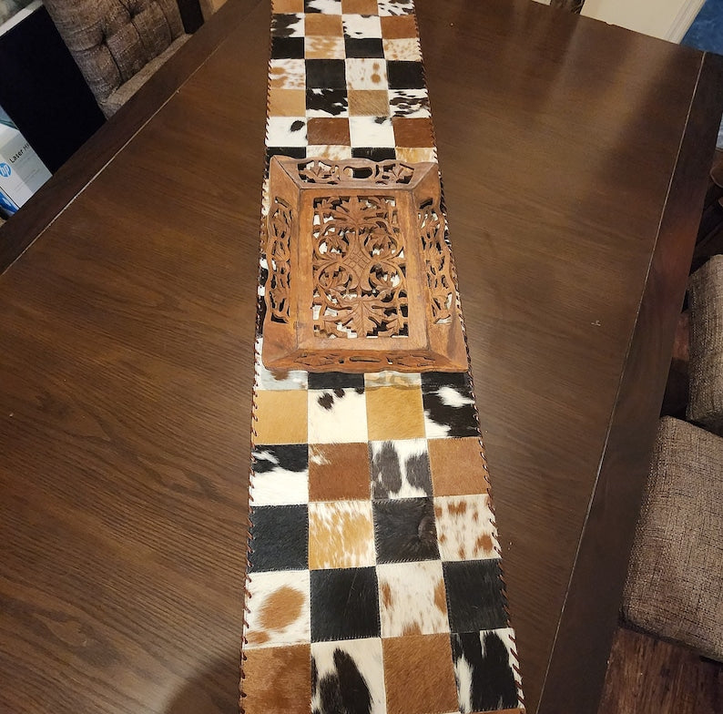 A stylish 16" x 96" leather cow skin table runner featuring a unique star pattern, perfect for enhancing home decor.