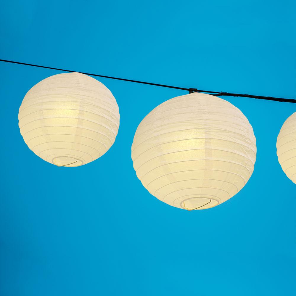 A set of colorful LED paper lantern lights hanging outdoors, illuminating a wedding venue with a warm glow.