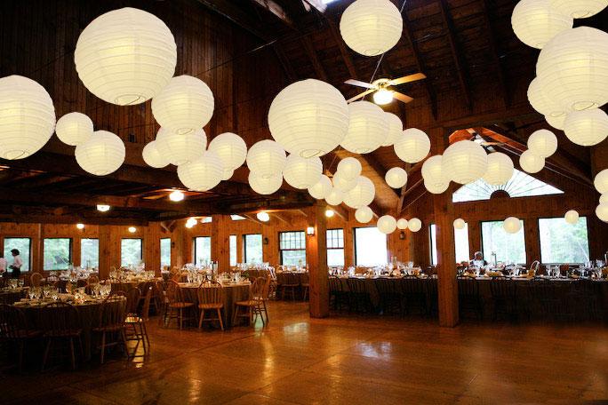 A set of colorful LED paper lantern lights hanging outdoors, illuminating a wedding venue with a warm glow.