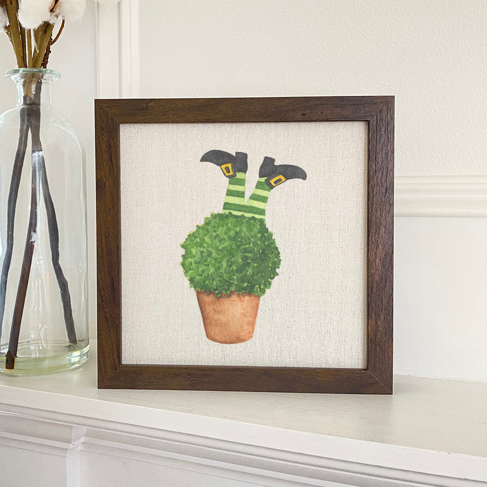Leprechaun Legs in Plant framed sign with a stylized wood frame, featuring eco-friendly printing on a linen-look background.