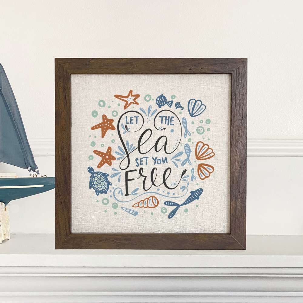 Framed sign with 'Let the Sea Set You Free' text, featuring a wood frame and linen-look background.