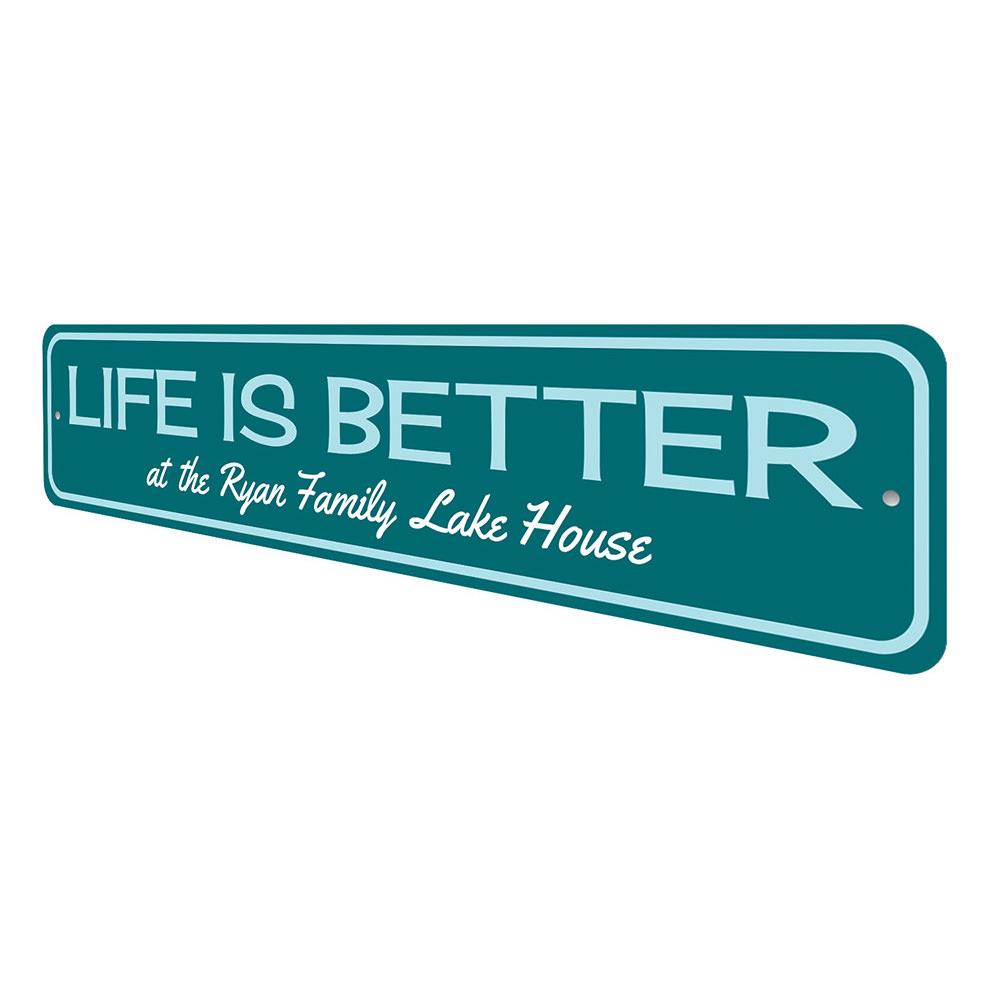 A decorative metal sign reading 'Life Is Better at the Lake', showcasing a beautiful lakeside theme, perfect for lakehouse decor.