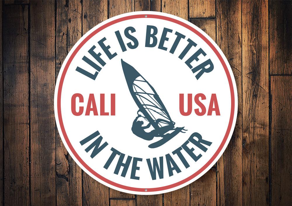 Decorative metal sign reading 'Life is Better in the Water', featuring a beach-themed design, perfect for coastal homes.