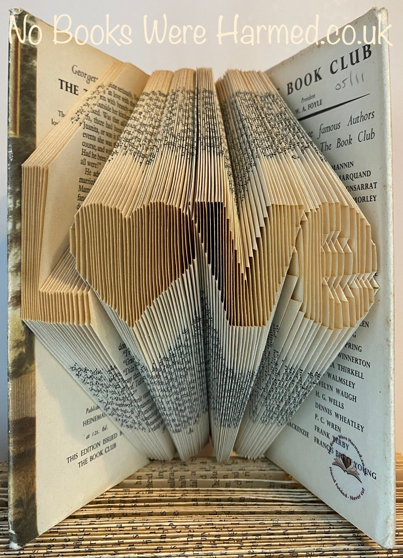 Hand-folded book art piece shaped as 'L♥ve' with a heart for 'o', crafted from vintage books.