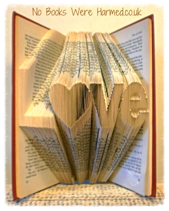 Hand-folded book art piece shaped as 'L♥ve' with a heart for 'o', crafted from vintage books.