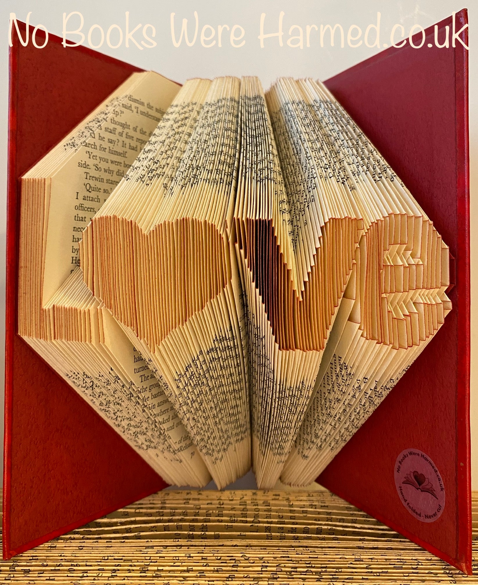 Hand-folded book art piece shaped as 'L♥ve' with a heart for 'o', crafted from vintage books.