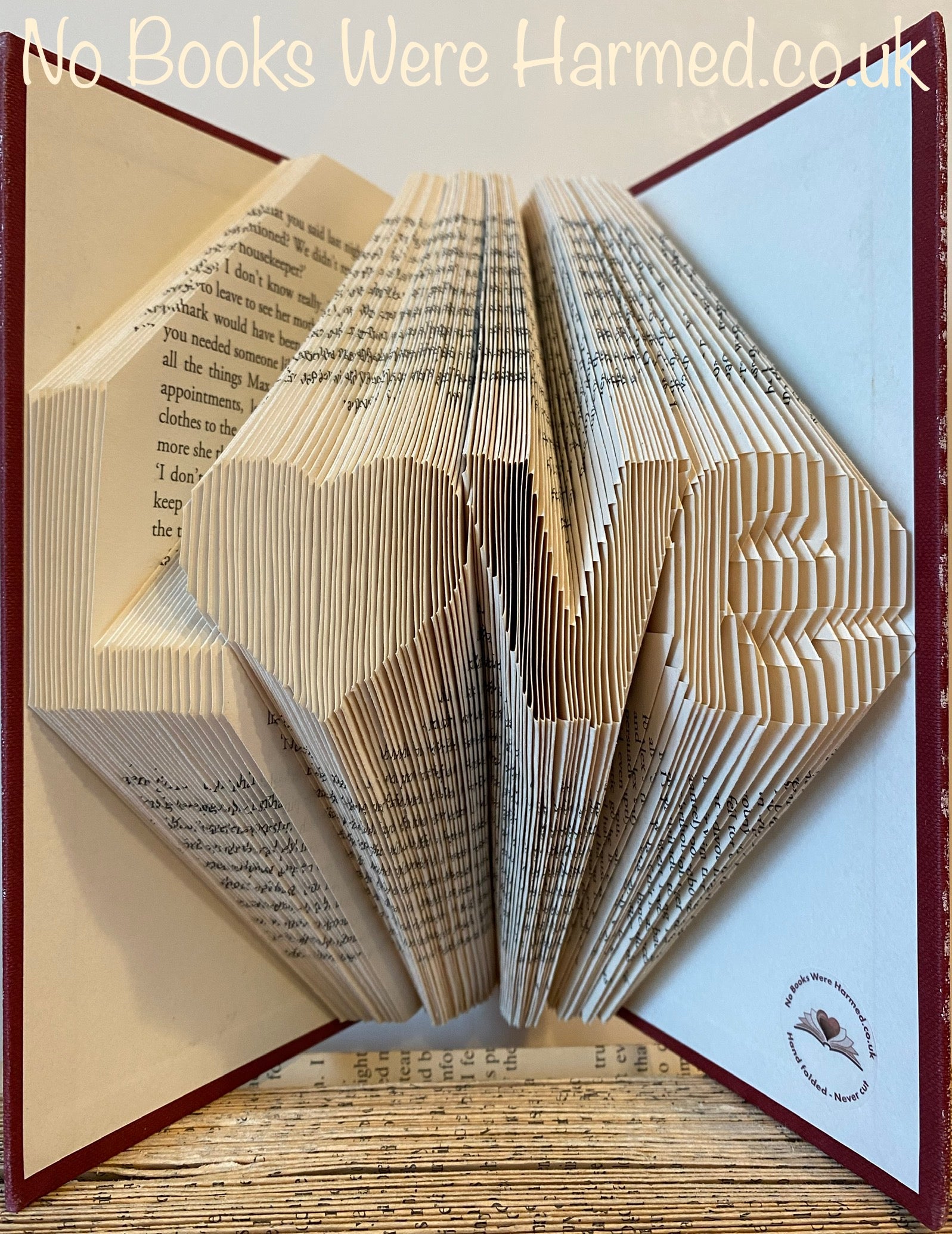 Hand-folded book art piece shaped as 'L♥ve' with a heart for 'o', crafted from vintage books.
