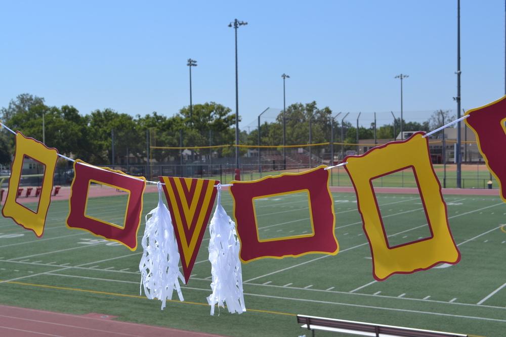 Maroon and gold party decoration set featuring paper frames, pennant, ribbon, and tassels.