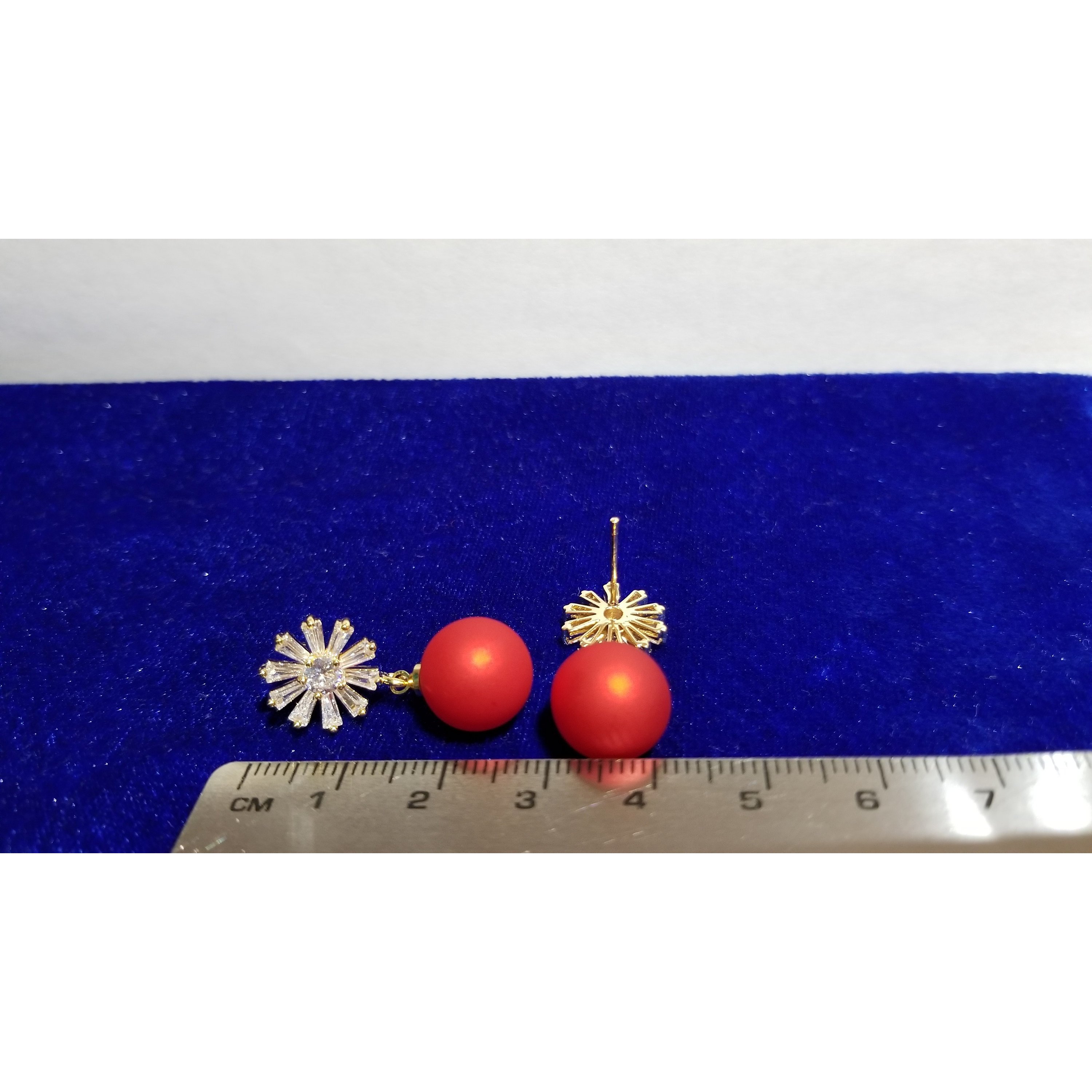 A close-up of red matte beads with a sparkling zircon stone stud, elegantly designed with 24k gold plating on brass.