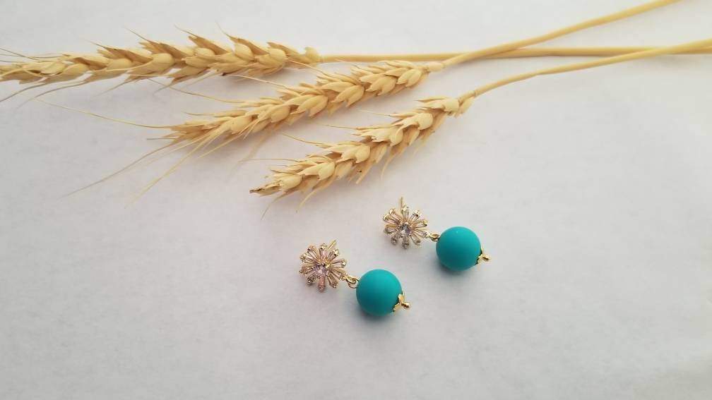 A close-up of red matte beads with a sparkling zircon stone stud, elegantly designed with 24k gold plating on brass.