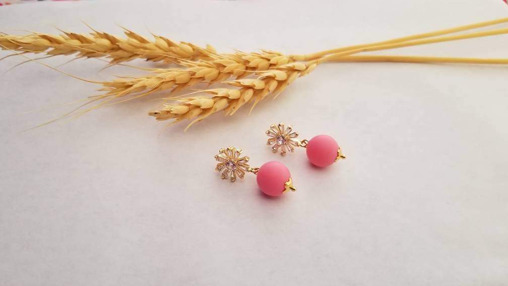 A close-up of red matte beads with a sparkling zircon stone stud, elegantly designed with 24k gold plating on brass.