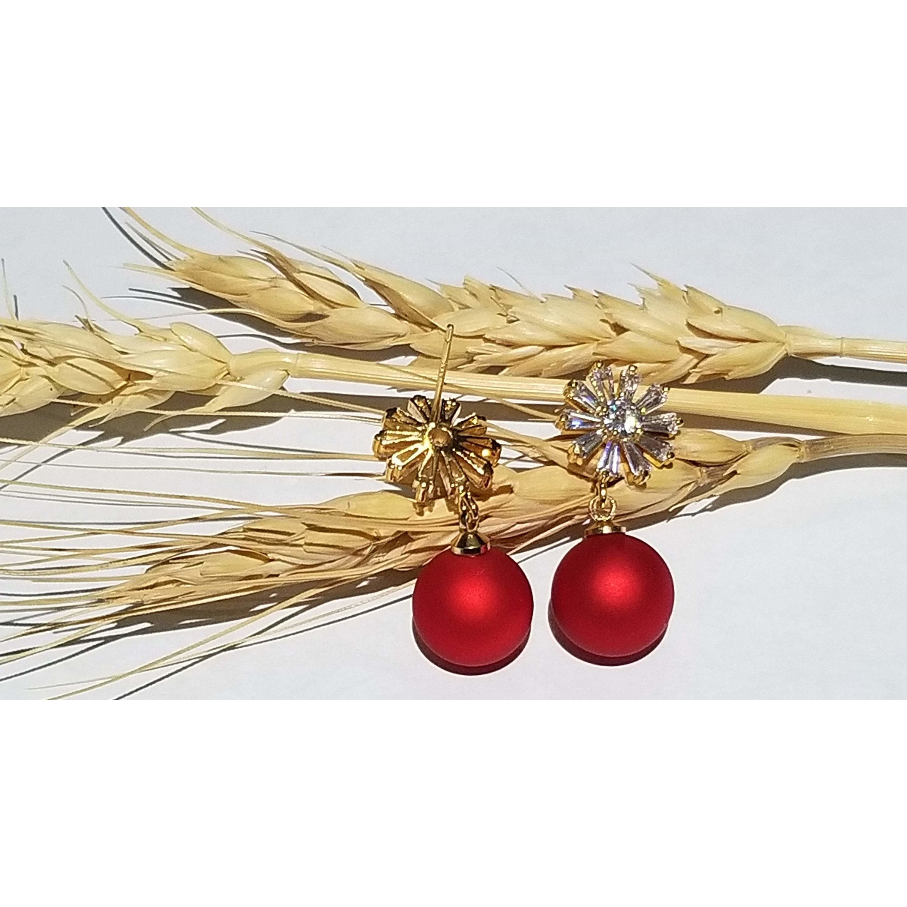 A close-up of red matte beads with a sparkling zircon stone stud, elegantly designed with 24k gold plating on brass.