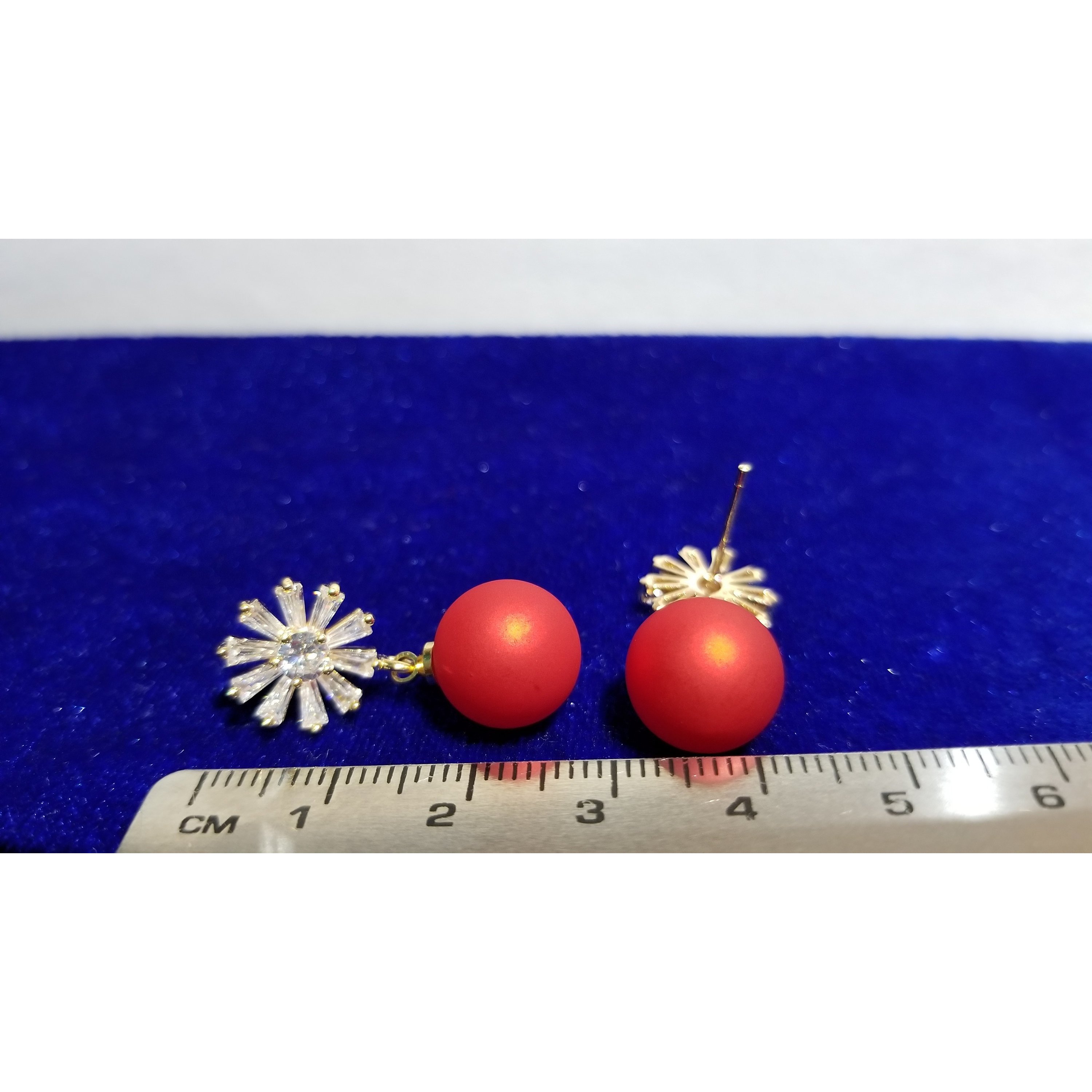 A close-up of red matte beads with a sparkling zircon stone stud, elegantly designed with 24k gold plating on brass.