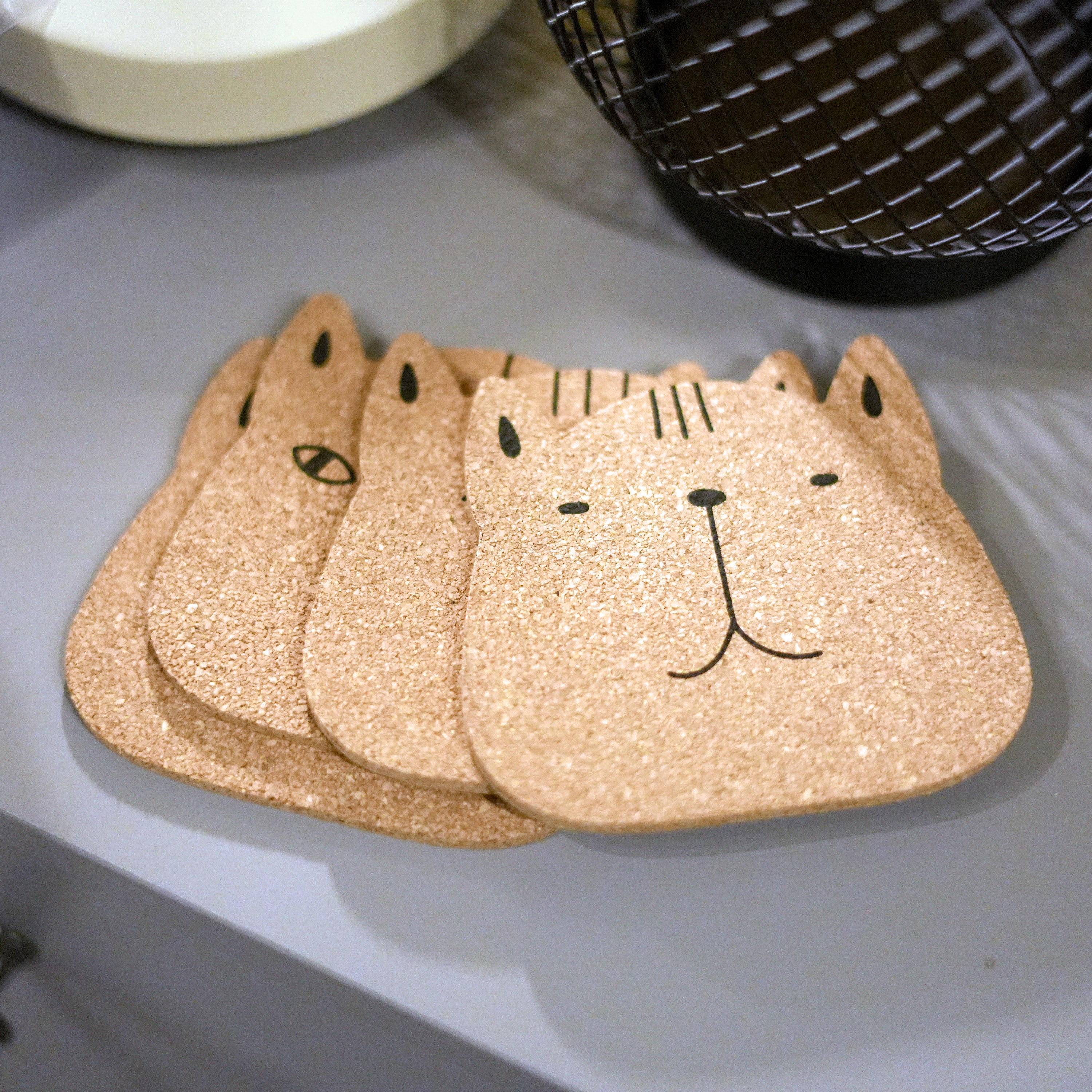 Set of 6 round cork coasters featuring different cute cat faces, perfect for protecting furniture and showcasing love for cats.