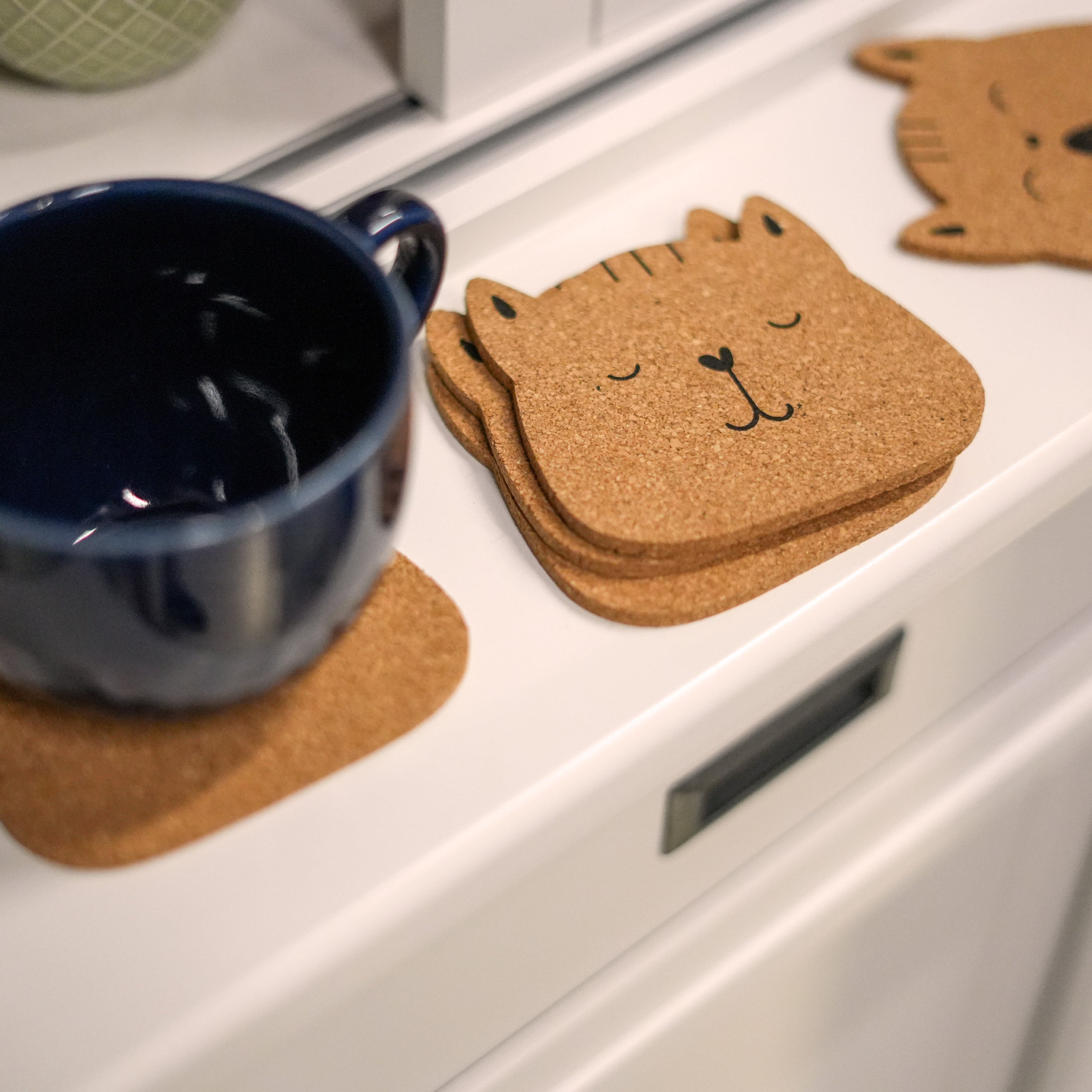 Set of 6 round cork coasters featuring different cute cat faces, perfect for protecting furniture and showcasing love for cats.