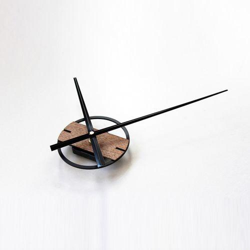 A modern wall clock featuring a metal and wood design, showcasing aluminum clock hands and a wooden base, perfect for home decor.