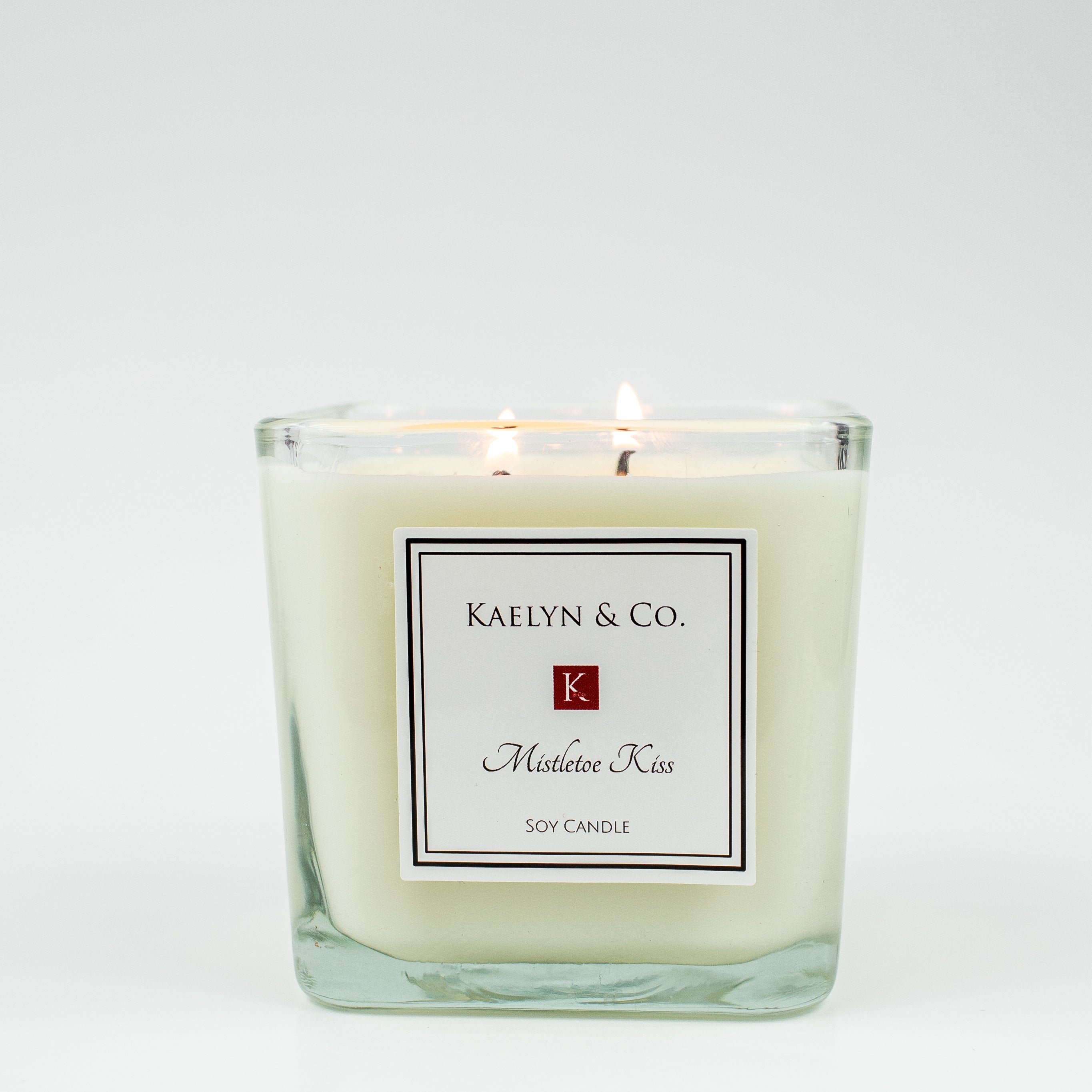 Mistletoe Kiss Medium Cube Candle with woodsy fir and sweet cherry scent, elegantly packaged in a box.