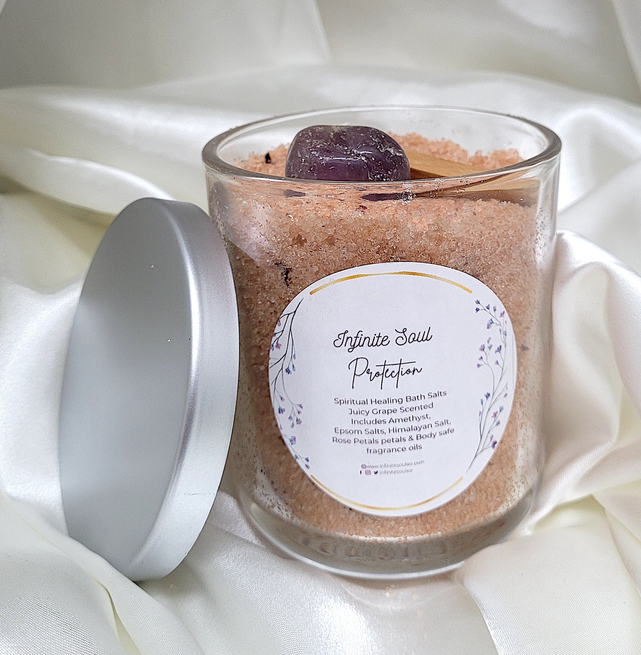 A jar of Negative Energy Be Gone bath salts with Amethyst crystals and rose petals, featuring a juicy grape scent.