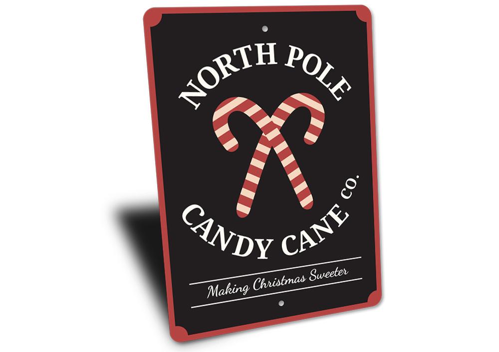 North Pole Candy Cane Company decorative sign made of aluminum, featuring festive colors and a charming design perfect for Christmas decorations.