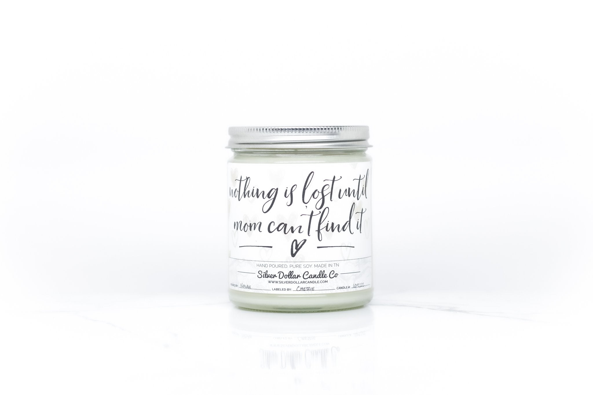 A humorous candle titled 'Nothing Is Lost Until Mom Can't Find It', showcasing a stylish design with a personalized lid option.