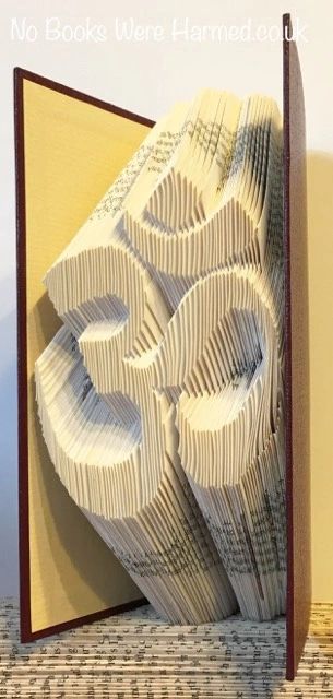 Handcrafted Om symbol art made from vintage book pages, showcasing intricate folds and unique design.