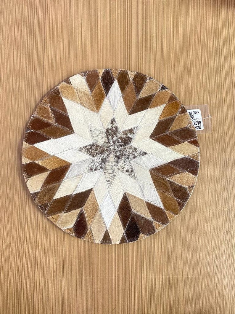 A set of four handcrafted 14-inch round cow skin placemats showcasing unique textures and colors, perfect for rustic dining settings.