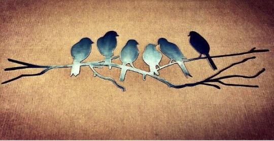 Metal wall art featuring six love birds perched on a branch, crafted from polished steel with a dark gray patina.