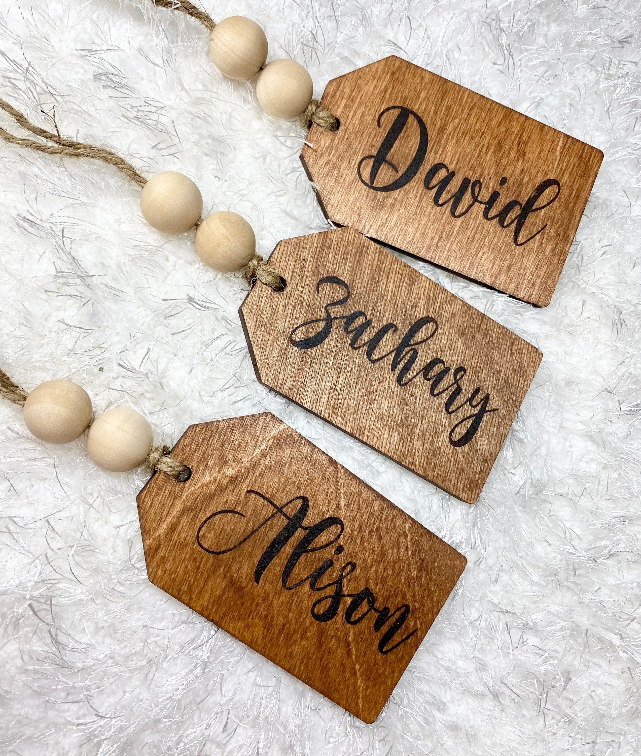Personalized wooden gift tags made of birch plywood with twine and wooden beads, perfect for various occasions.
