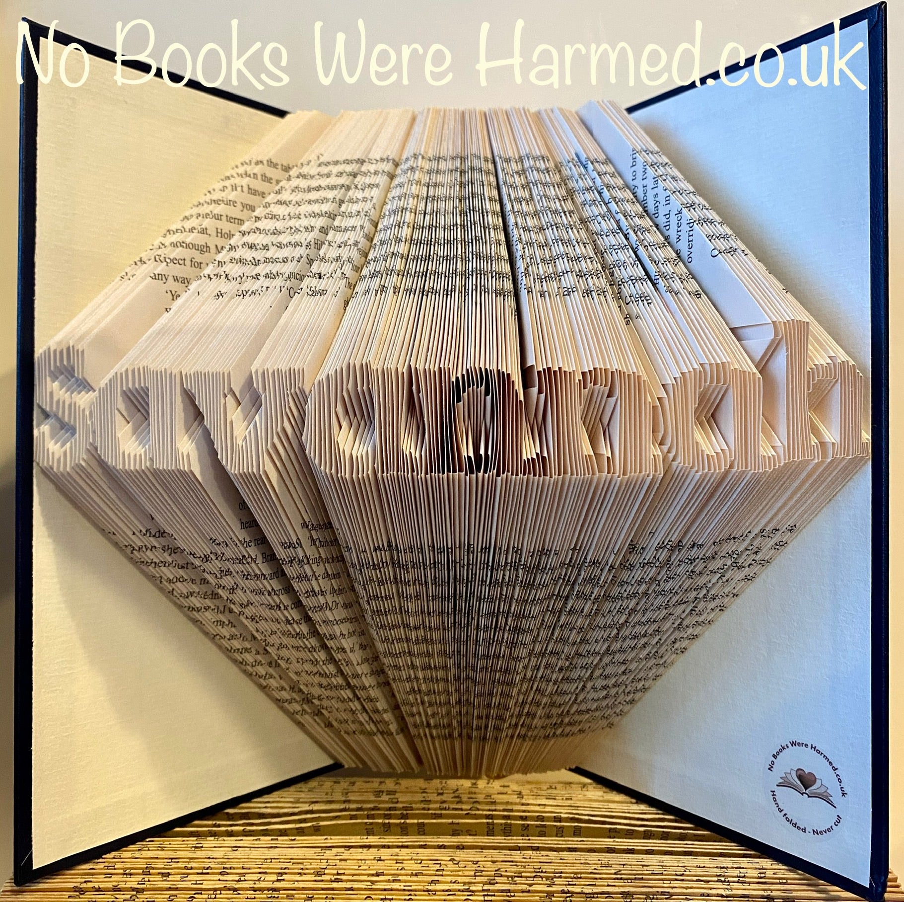 Hand-folded book art displaying a custom word, showcasing unique vintage pages and intricate lettering.