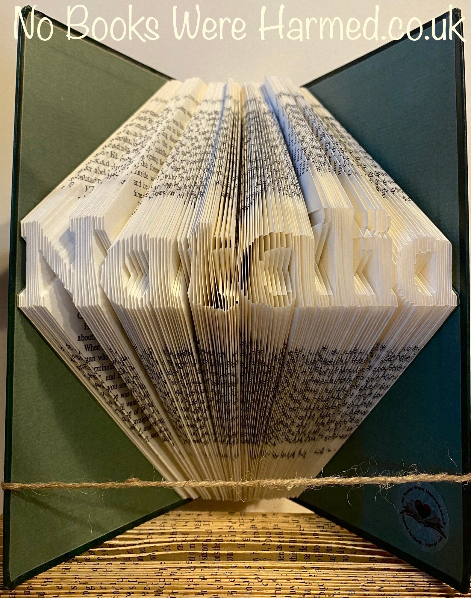 Hand-folded book art displaying a custom word, showcasing unique vintage pages and intricate lettering.