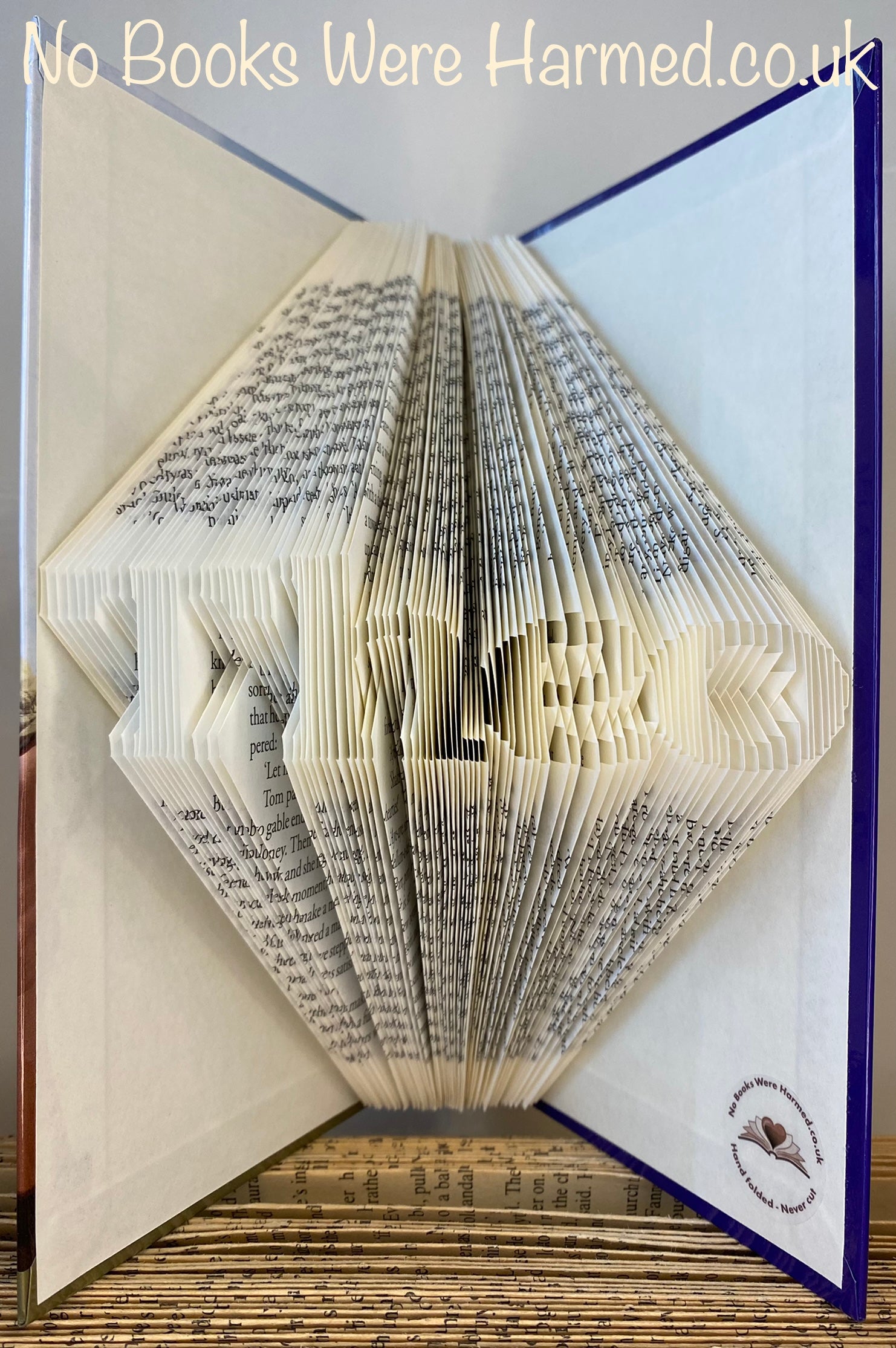 Hand-folded book art displaying a custom word, showcasing unique vintage pages and intricate lettering.