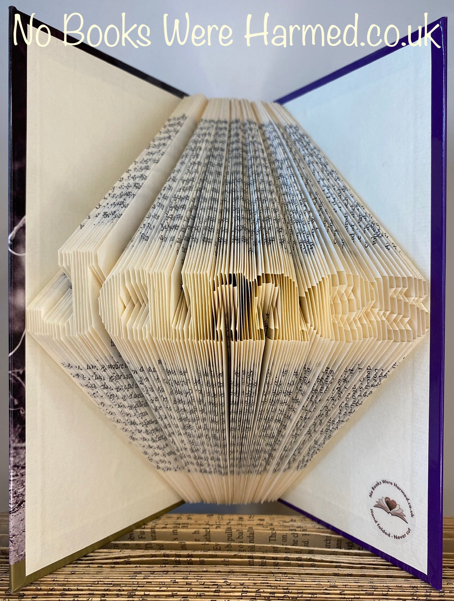 Hand-folded book art displaying a custom word, showcasing unique vintage pages and intricate lettering.