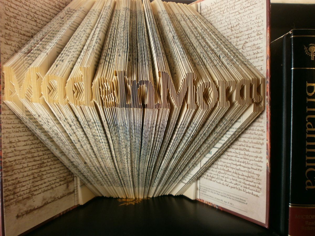 Hand-folded book art displaying a custom word, showcasing unique vintage pages and intricate lettering.