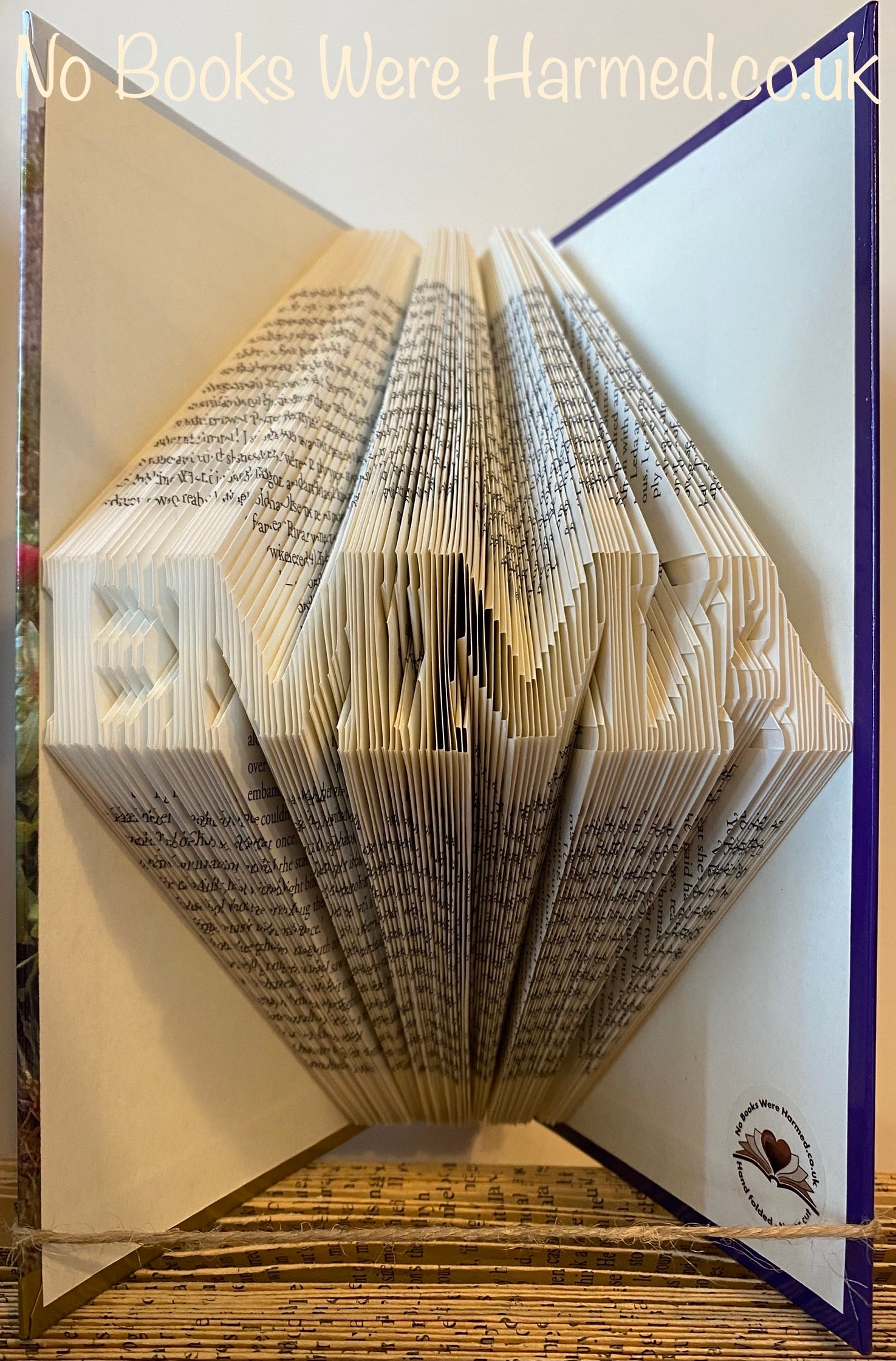 Hand-folded book art displaying a custom word, showcasing unique vintage pages and intricate lettering.