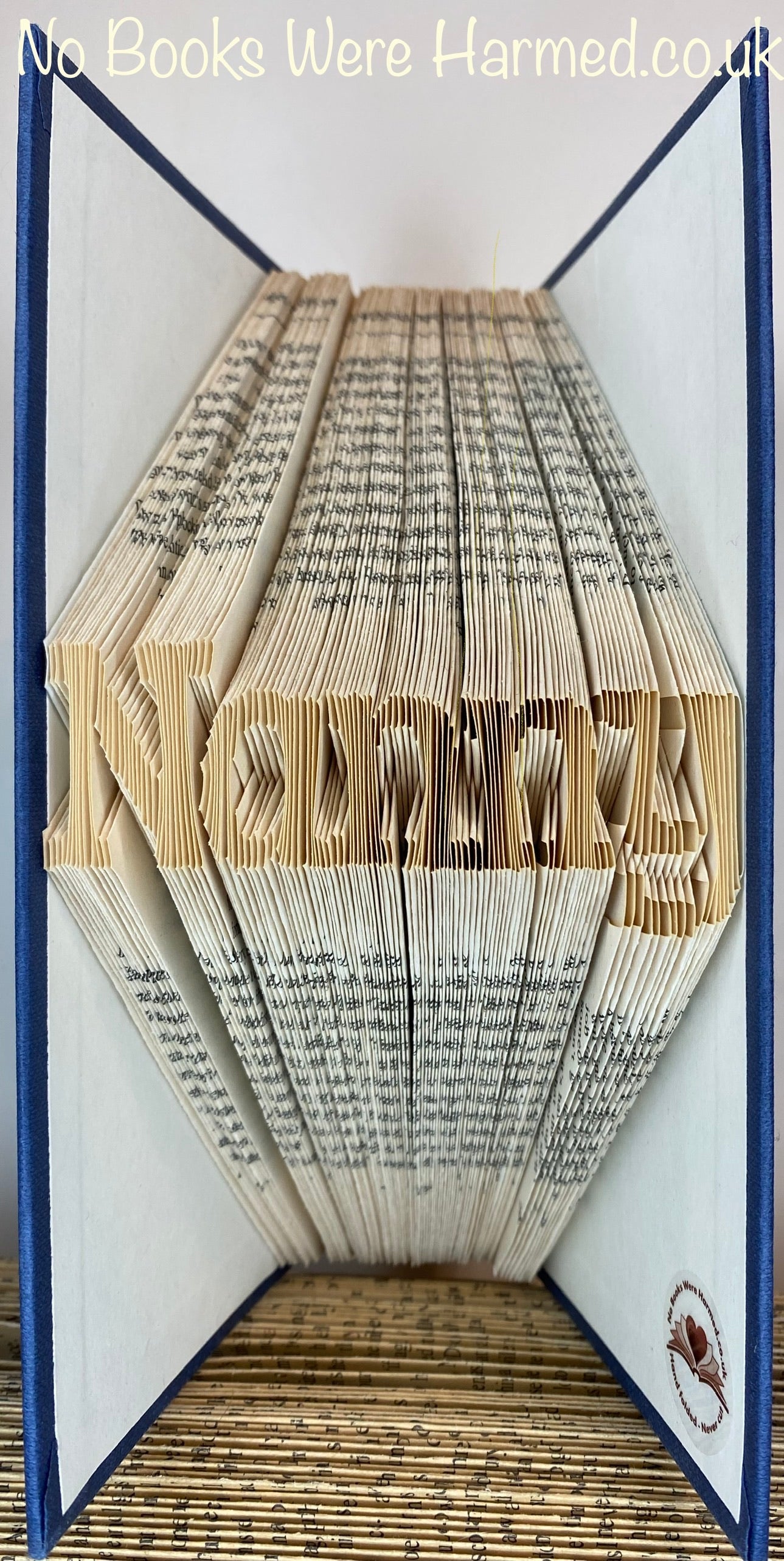 Hand-folded book art displaying a custom word, showcasing unique vintage pages and intricate lettering.