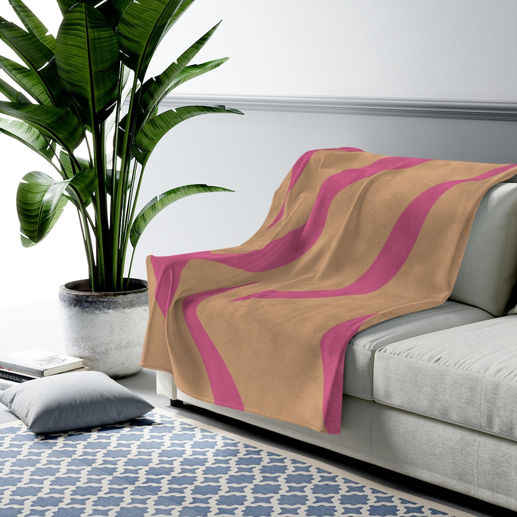 A cozy pink and orange leopard stripes plush throw blanket draped elegantly over a couch, showcasing its soft velveteen texture and vibrant colors.